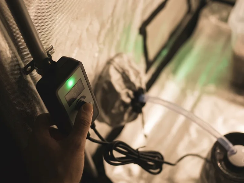 A plug-in humidity controller mounted on a grow tent pole