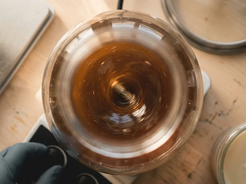 A vortex spinning in a flask of amber liquid culture on a stir plate